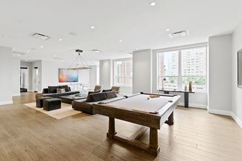 A billiard table is in the middle of a spacious room with a pool table and a couch.